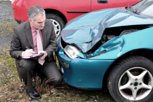 insurance agent sizing up car damage